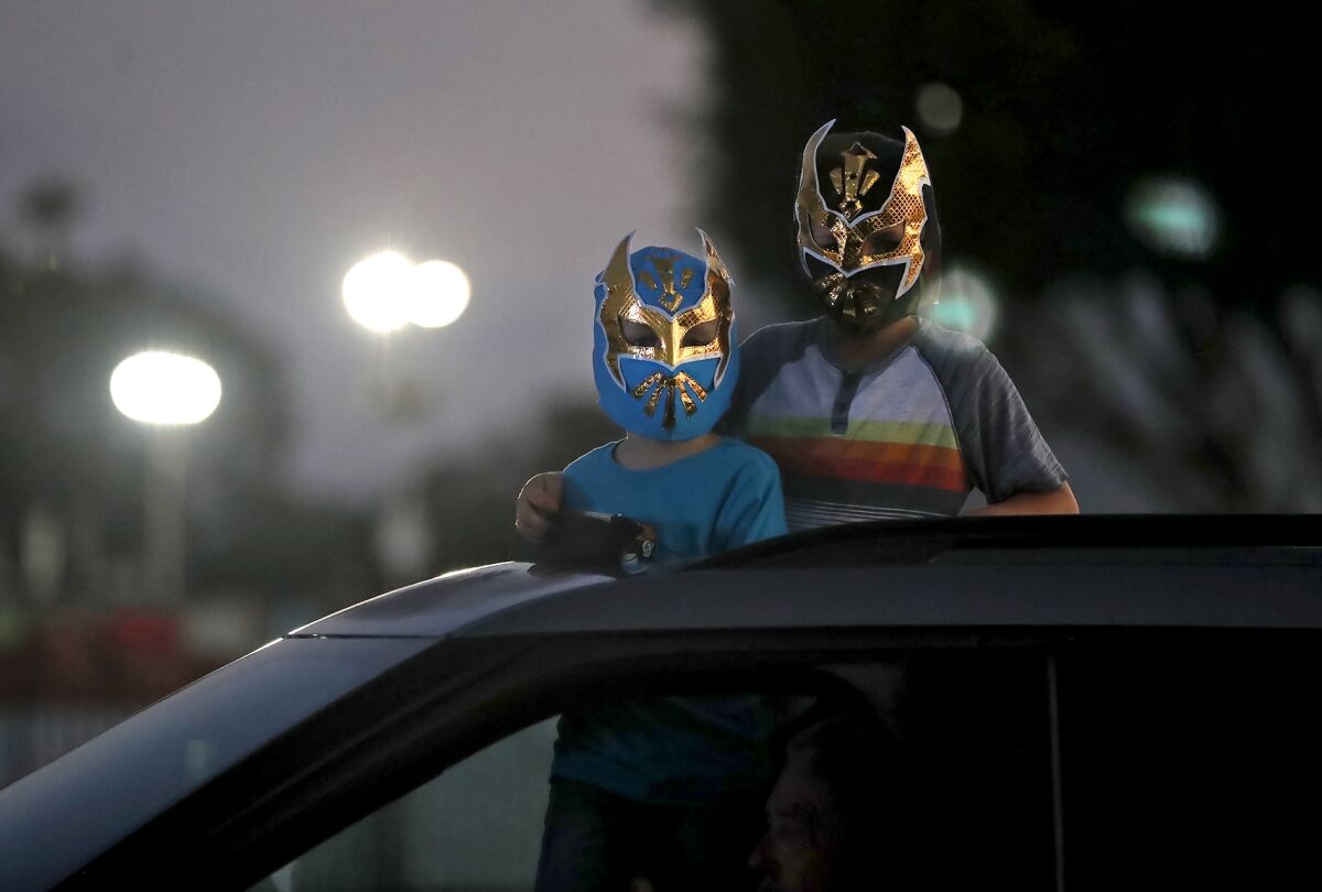 Kerrik Mayfield, left, and James Mayfield VI wear their lucha libre masks as they watch the drive-in wrestling show.