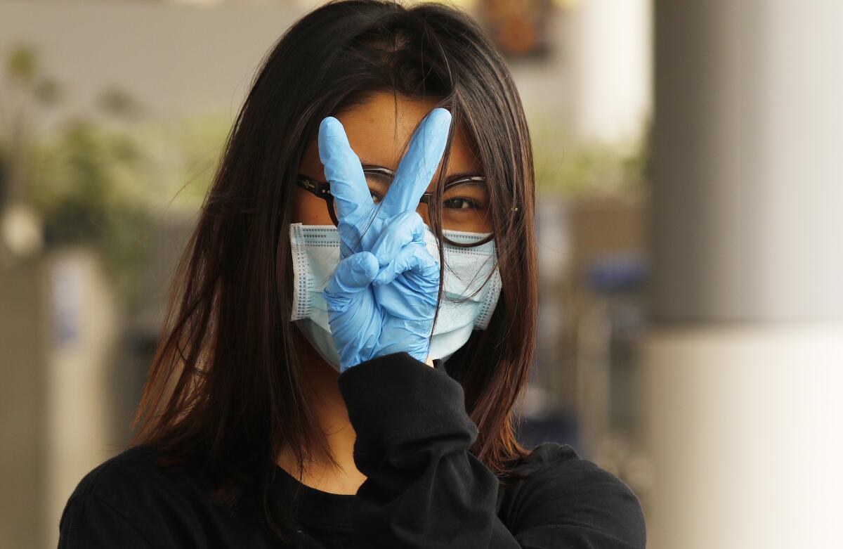 Yiran Zou, a student at the California College of Art in San Francisco, prepares to fly home to China from Los Angeles International Airport, where all travelers must wear face coverings.