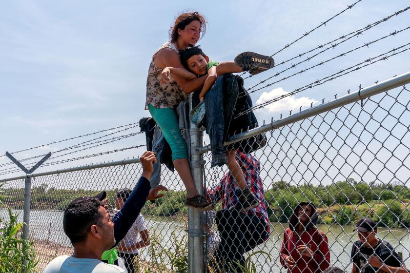 TOPSHOT - Migrants climb over a barbed wire fence after crossing the Rio Grande into US from Mexico, in Eagle Pass, Texas on August 25, 2023. (Photo by SUZANNE CORDEIRO / AFP) (Photo by SUZANNE CORDEIRO/AFP via Getty Images)