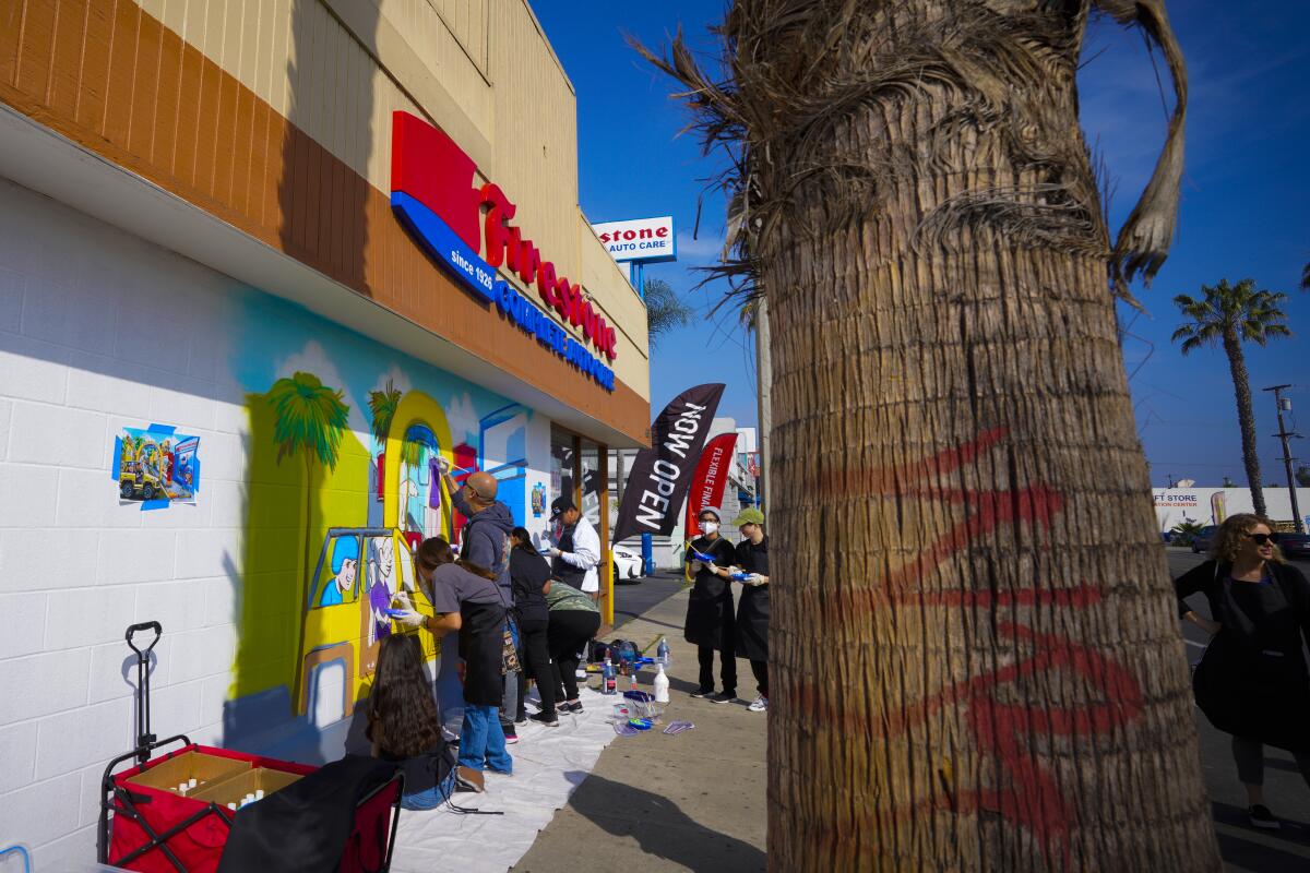 Chula Vista, CA - March 26: A group of volunteers paints a mural on the side of a local auto shop business wall on Broadway.