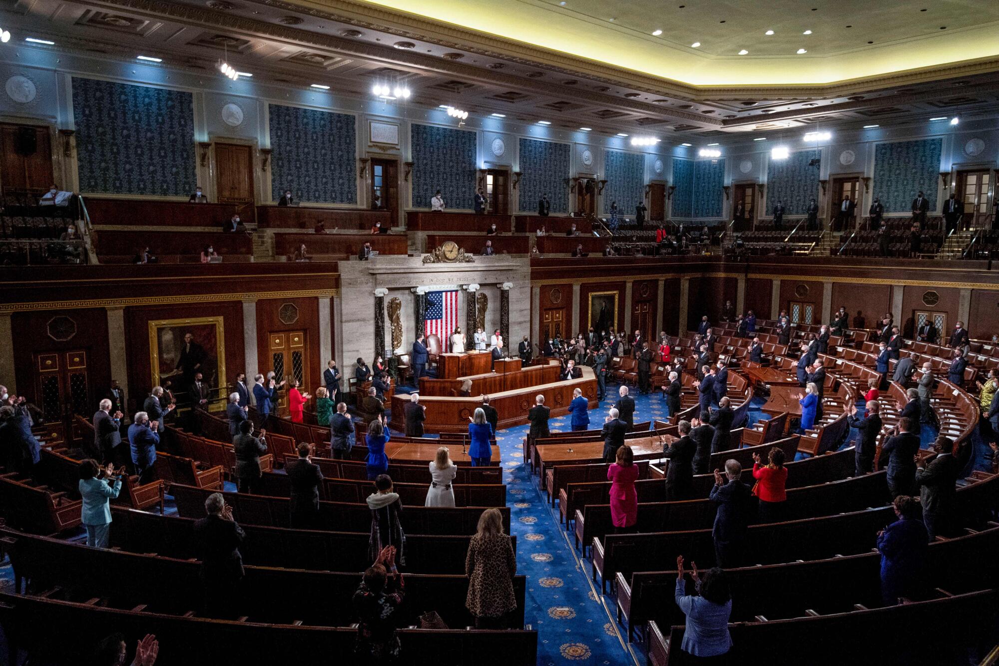 People stand up in a lightly occupied chamber.