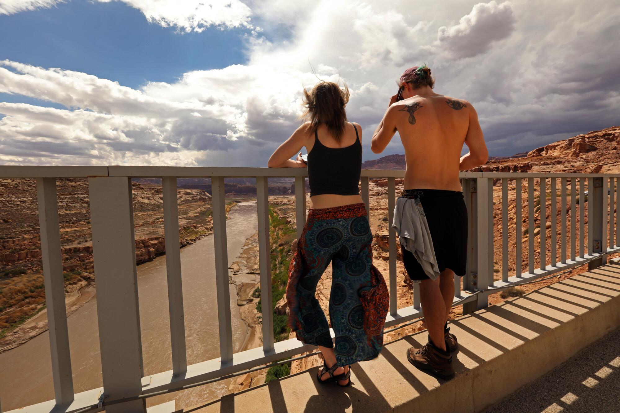 Two people look out over a bridge toward a river