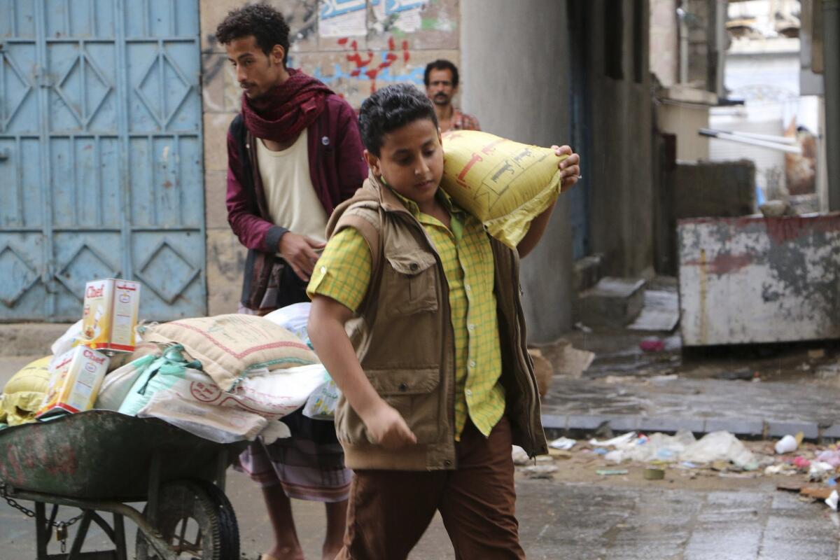 A boy carries a bag of sugar to his family during a food distribution May 6 by Yemeni volunteers in the city of Taizz. Yemenis have suffered through shortages caused by the conflict.