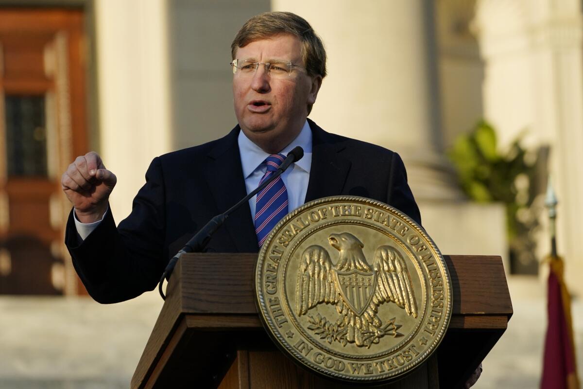 A man gesturing as he speaks at a lectern bearing Mississippi's state seal.