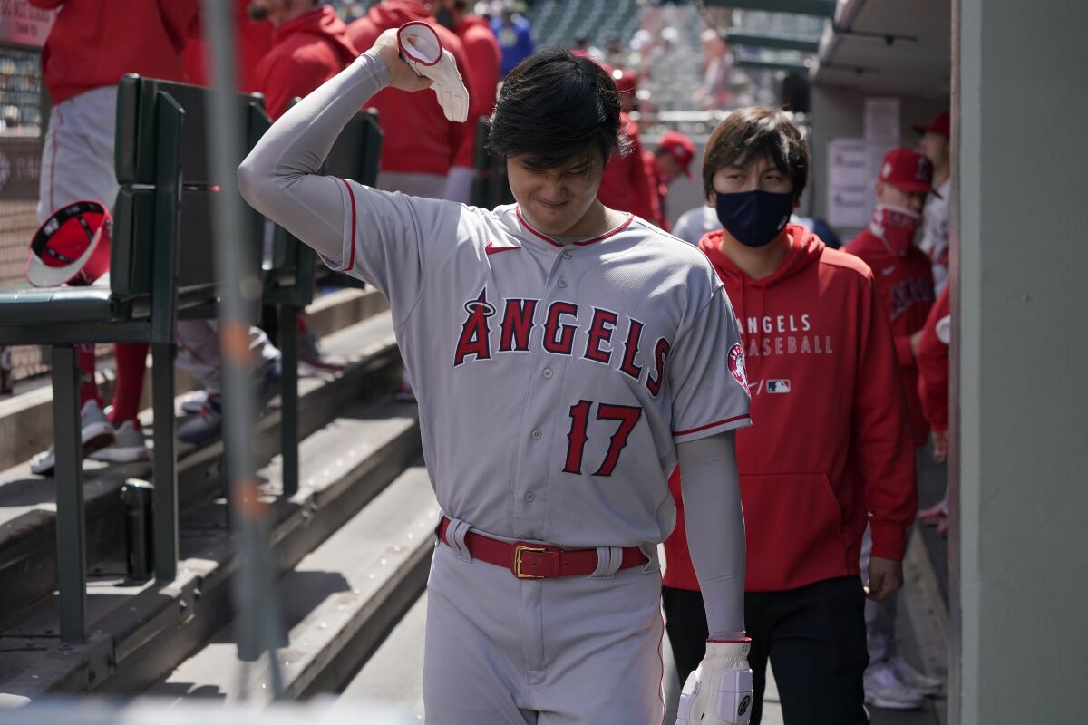 Shohei Ohtani holds up his arm as he heads into the clubhouse after taking a pitch off his elbow in the first inning Sunday.