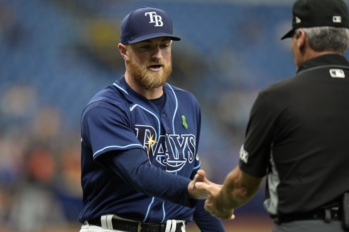 Tampa Bay Rays starting pitcher Drew Rasmussen gets his hands checked by first base umpire Angel Hernandez for foreign substances during the fourth inning of a baseball game against the Detroit Tigers Wednesday, May 18, 2022, in St. Petersburg, Fla. (AP Photo/Chris O'Meara)