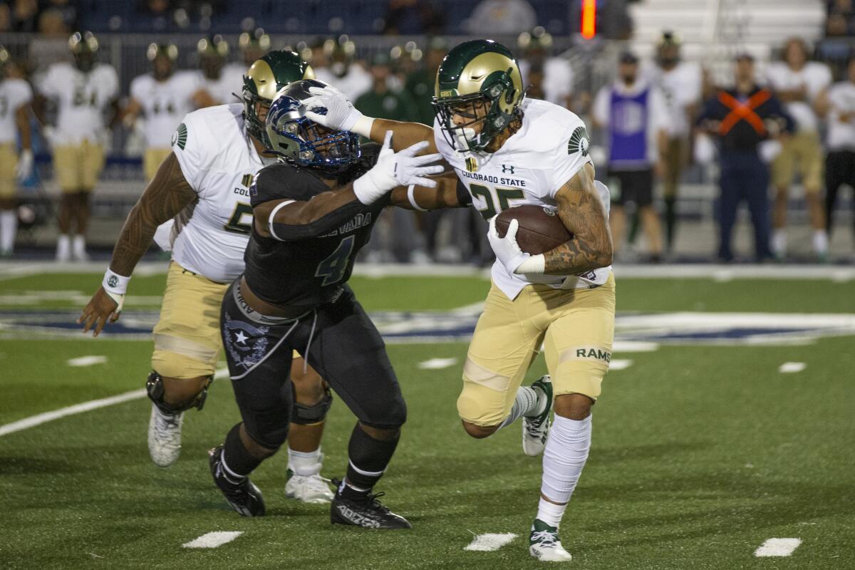 Colorado State running back Avery Morrow (25) stiff-arms Nevada linebacker Eli'jah Winston (4) iduringthe first half of an NCAA college football game in Reno, Nev., Friday, Oct. 7, 2022. (AP Photo/Tom R. Smedes)