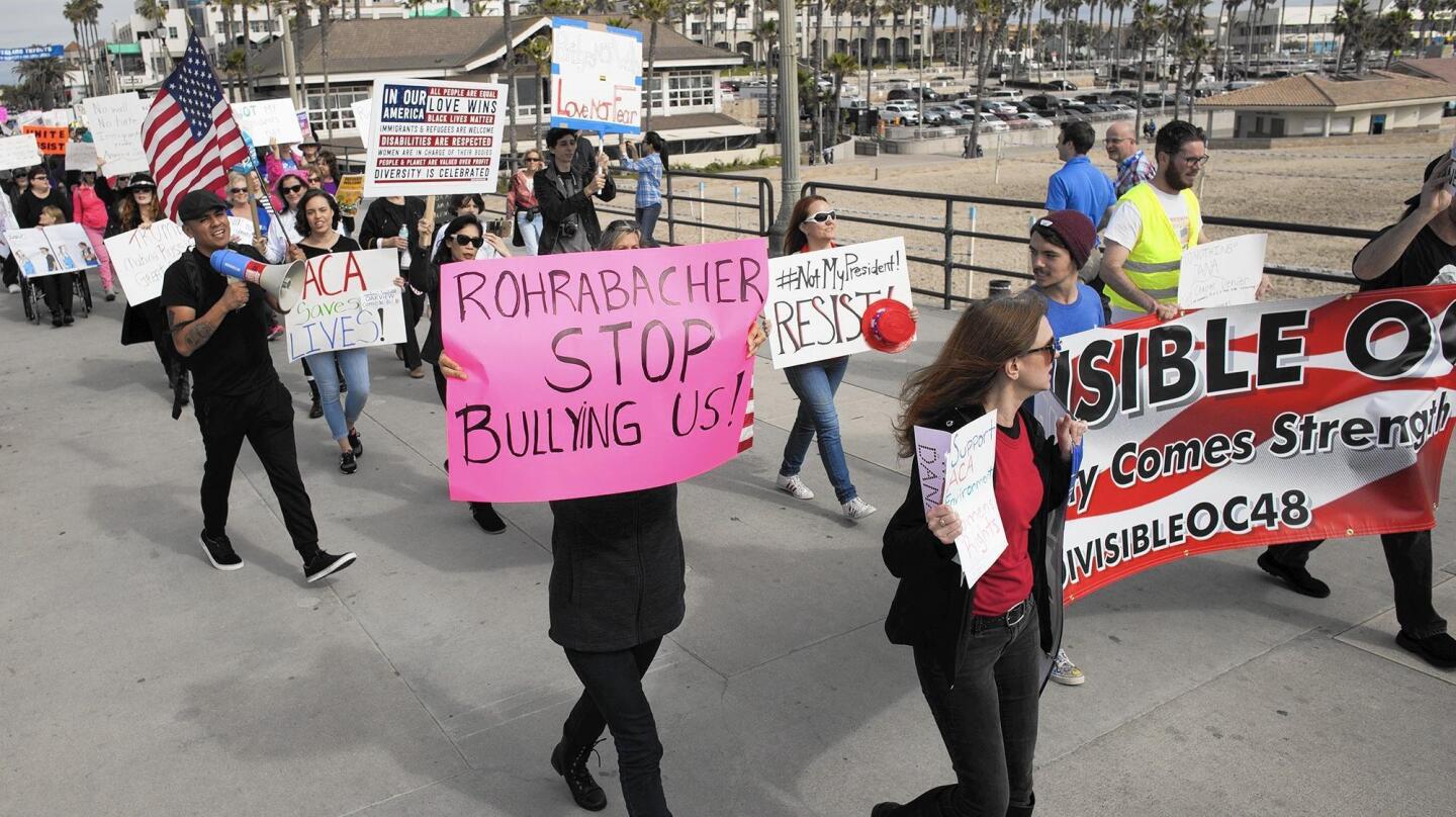 Protesters opposing Rep. Dana Rohrabacher's (R-Costa Mesa) support for President Trump and opposing Trump march along the pier in Huntington Beach on Monday.