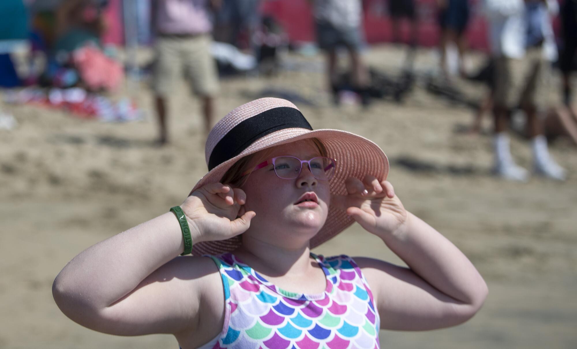 Emma Lewis, 8, of Las Vegas plugs her ears as a Navy EA-18 Growler flies over