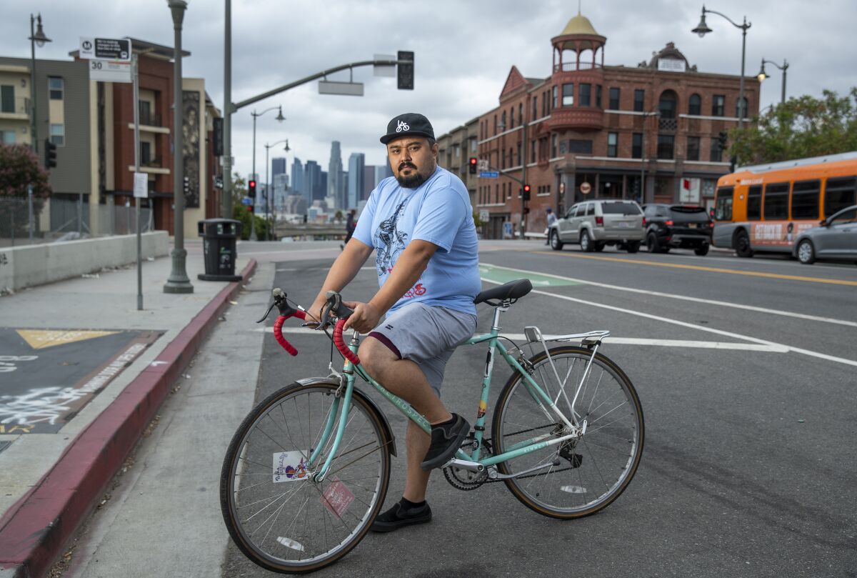 A man straddles his bike on a city street
