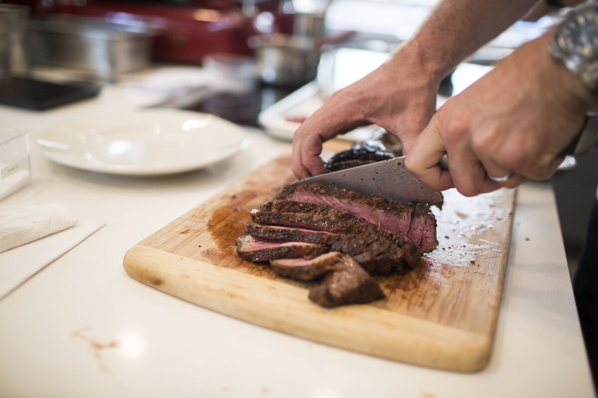 Australian Chef Curtis Stone cuts into a large rib-eye steak in his test kitchen in Beverly Hills.
