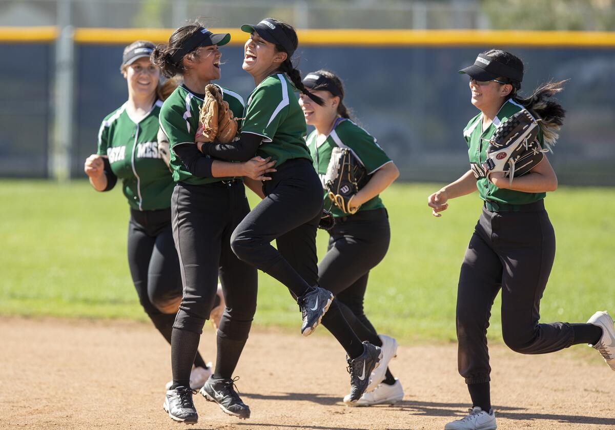 Costa Mesa's Joseline Cruz jumps into the arms of Megan Yat, left, after making a catch in center field against CdM.