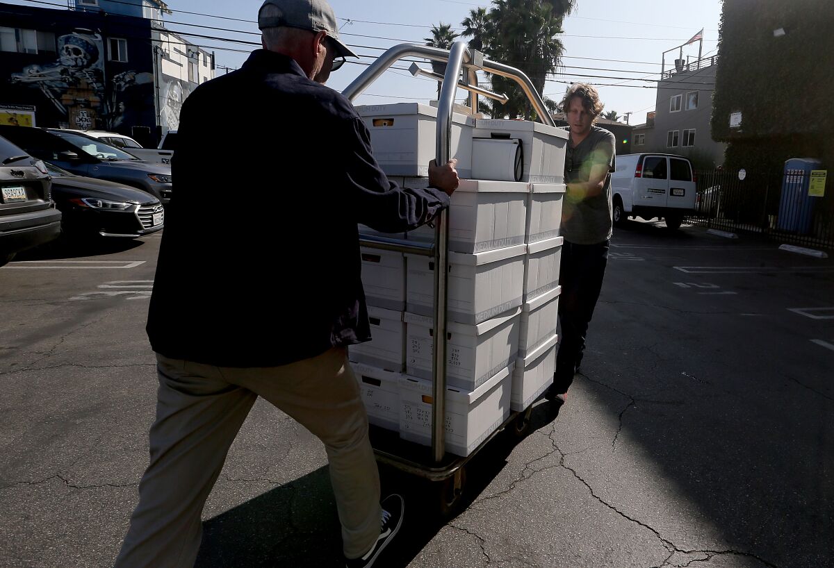 Volunteers for a recall campaign to oust L.A. City Councilman Mike Bonin wheel signed petitions to a van in Venice Beach.