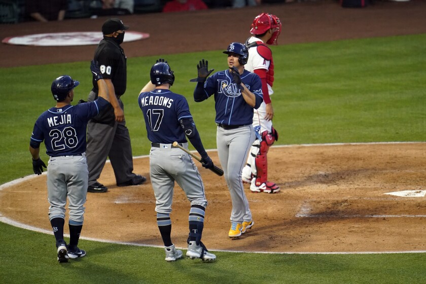 Tampa Bay Rays' Willy Adames, center right, is high-fived by Austin Meadows (17) after Adames scored on a single by Mike Brosseau during the third inning of a baseball game against the Los Angeles Angels Monday, May 3, 2021, in Anaheim, Calif. (AP Photo/Marcio Jose Sanchez)