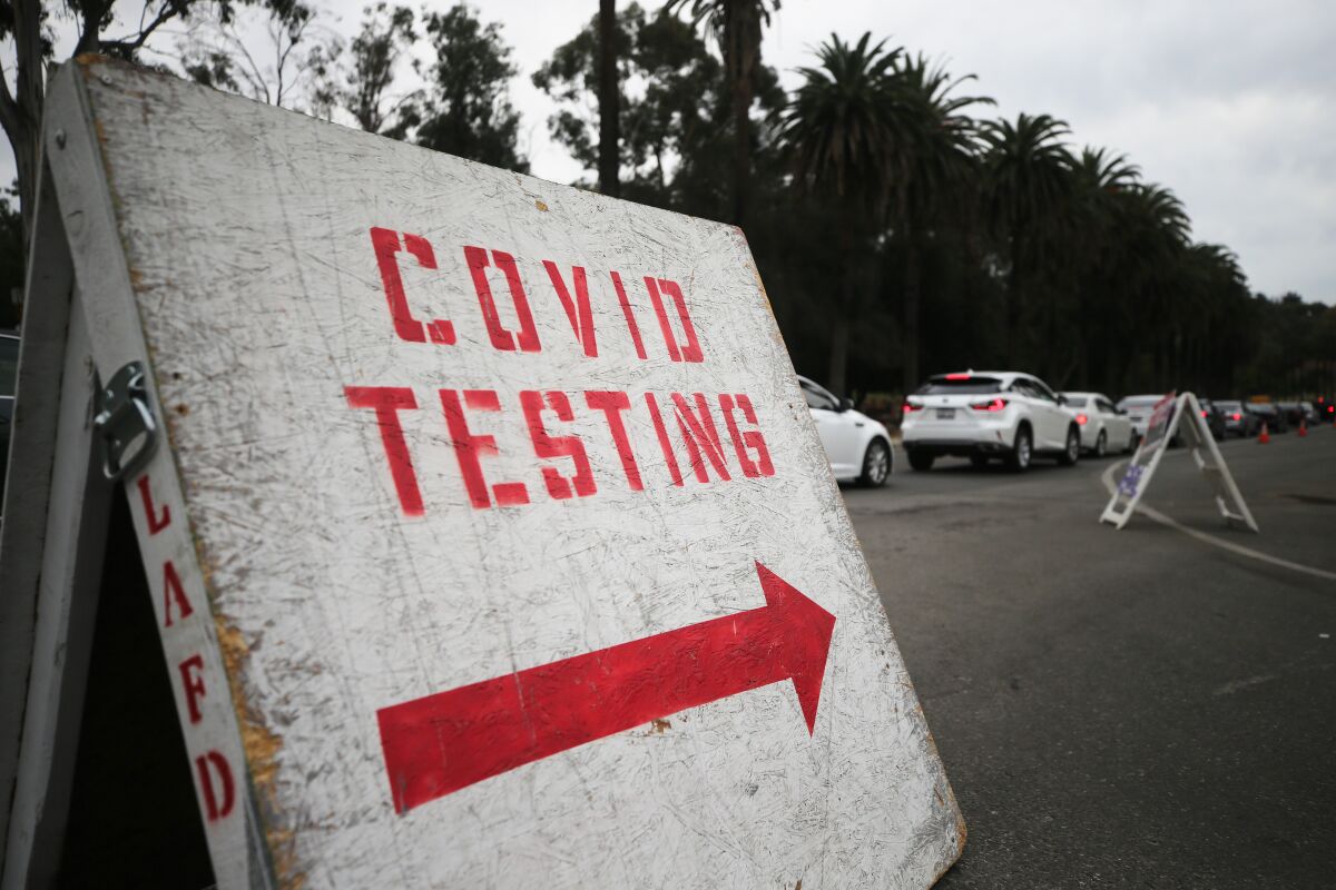 Vehicles line up to enter a COVID-19 testing site at Dodger Stadium on the first day of new stay-at-home orders.