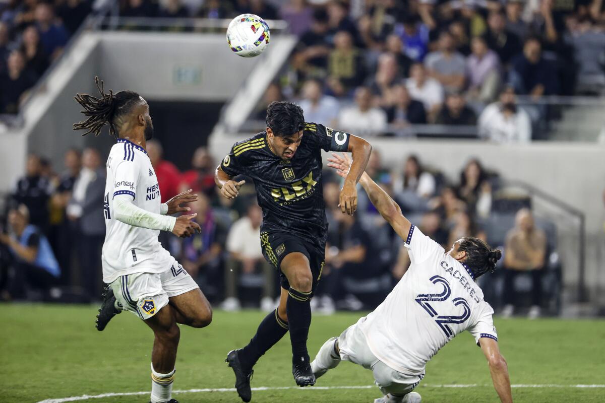 LAFC forward Carlos Vela goes for the ball between Galaxy forward Raheem Edwards, left, and defender Martin Caceres.