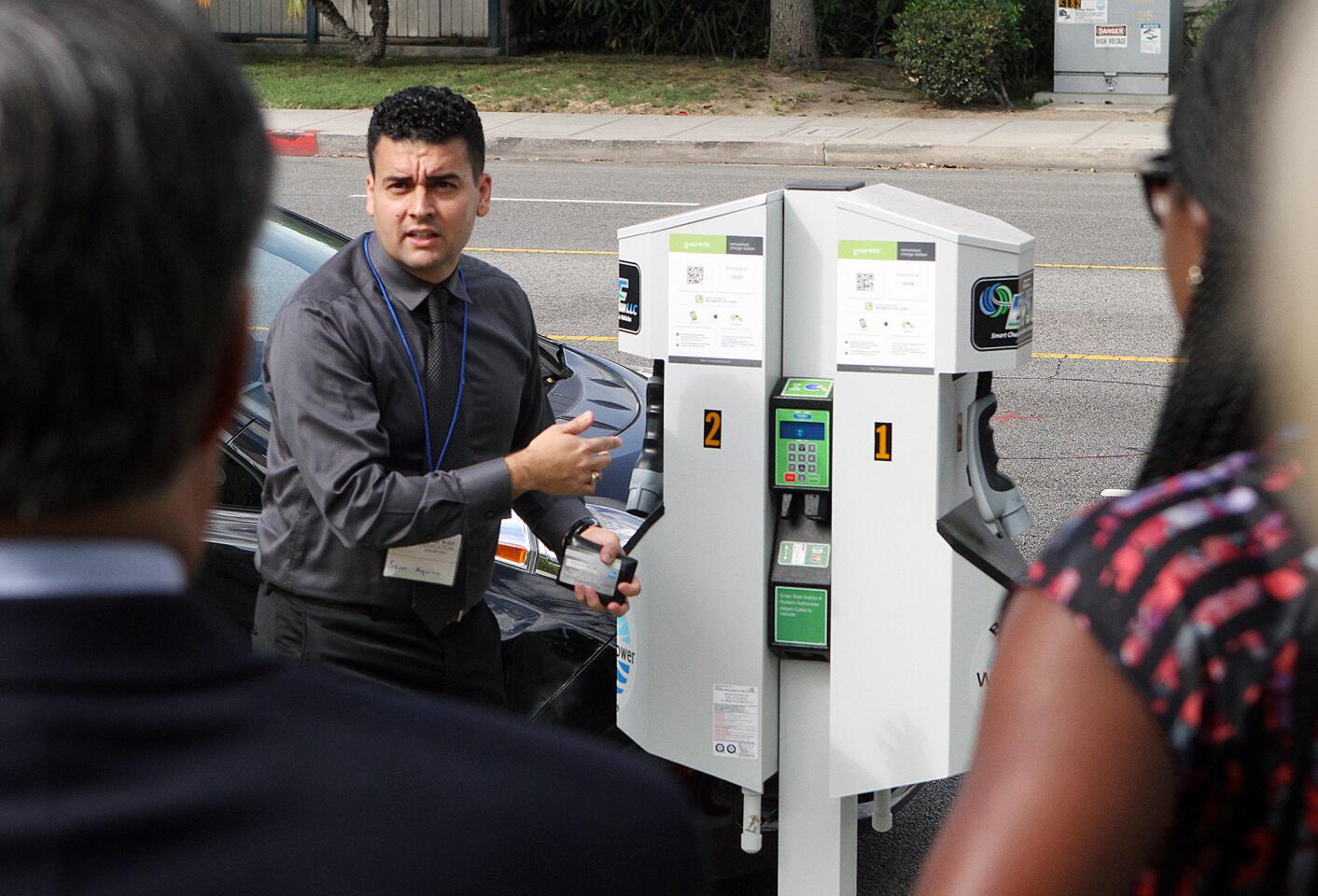 Burbank Water and Power's Sean Aquino demonstrates how an EV charging station works at a ribbon cutting for one of the eight dual-charger, electric-vehicle charging stations on Buena Vista Avenue in front of the Buena Vista Branch Library in Burbank on Tuesday, Aug. 25, 2015.