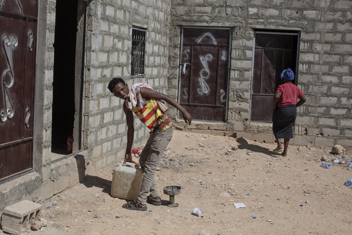 Tigra Hara Rayye, 23, an Ethiopian who came to Yemen a year ago, carries a jerry can of water in a compound for migrants.