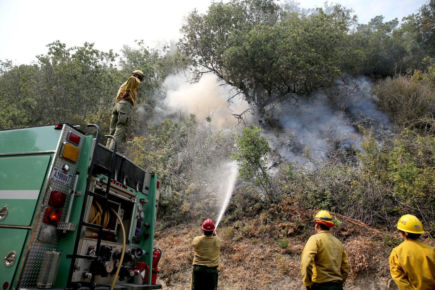 U.S. Forest Service firefighters put out spot fires from the Whittier fire along State Route 154 in the Los Padres National Forest near Lake Cachuma.