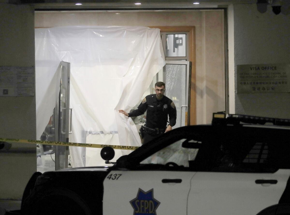 An officer walks through plastic sheeting that covers the opening to a building.