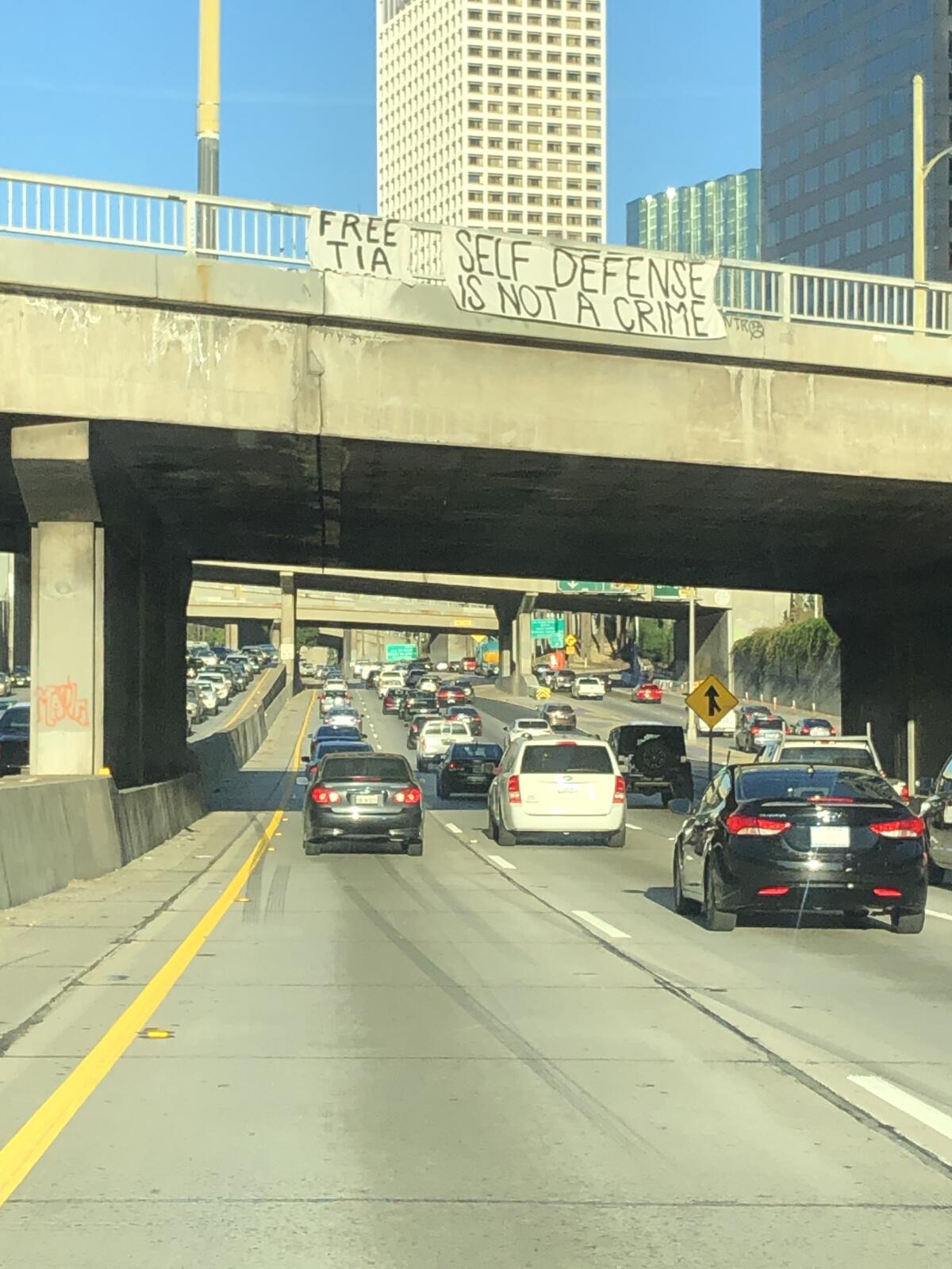 Signs hanging from freeway overpass say "Free Tia" and "Self defense is not a crime"
