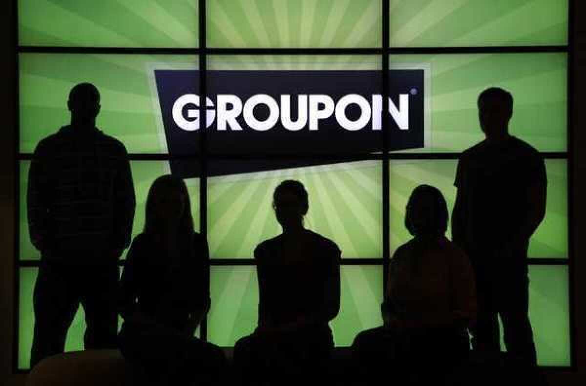 Employees at Groupon Inc. pose with the company logo. A Wall Street Journal report says regulators may be probing a pre-earnings Groupon stock surge.