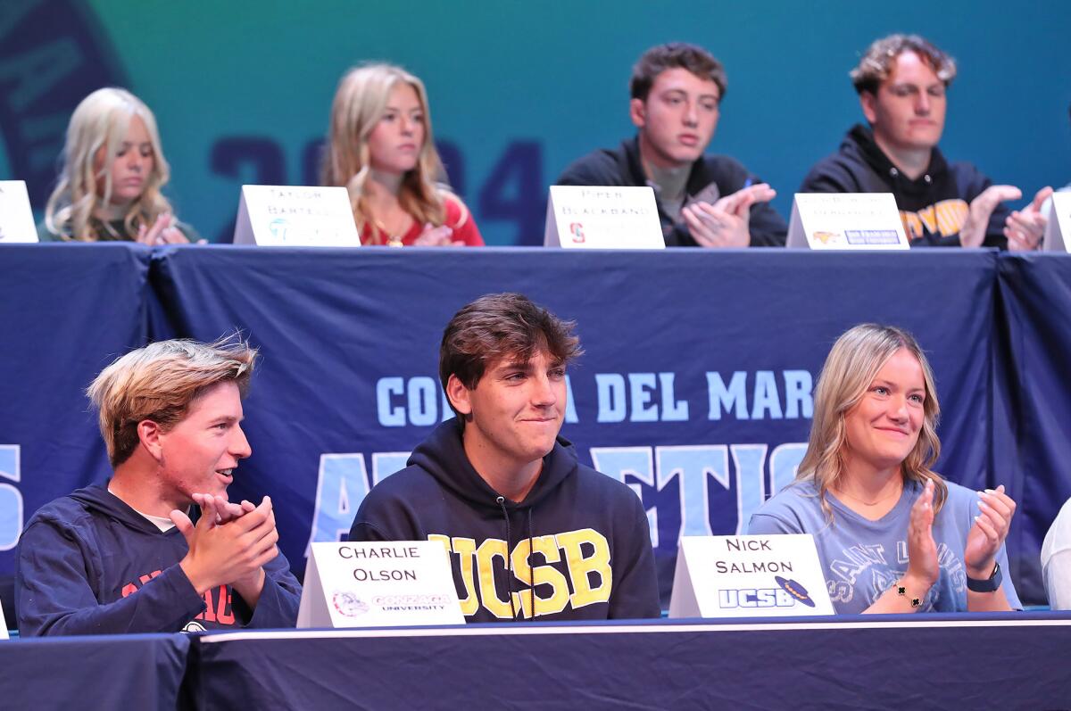 Charlie Olson, Nick Salmon and Abigail Schalow join others during an ovation at signing day.