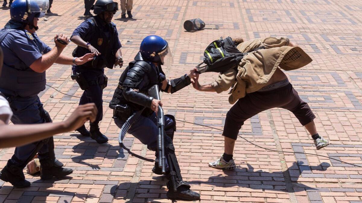 A police officer grabs a student on campus at the University of Witwatersrand in Johannesburg.