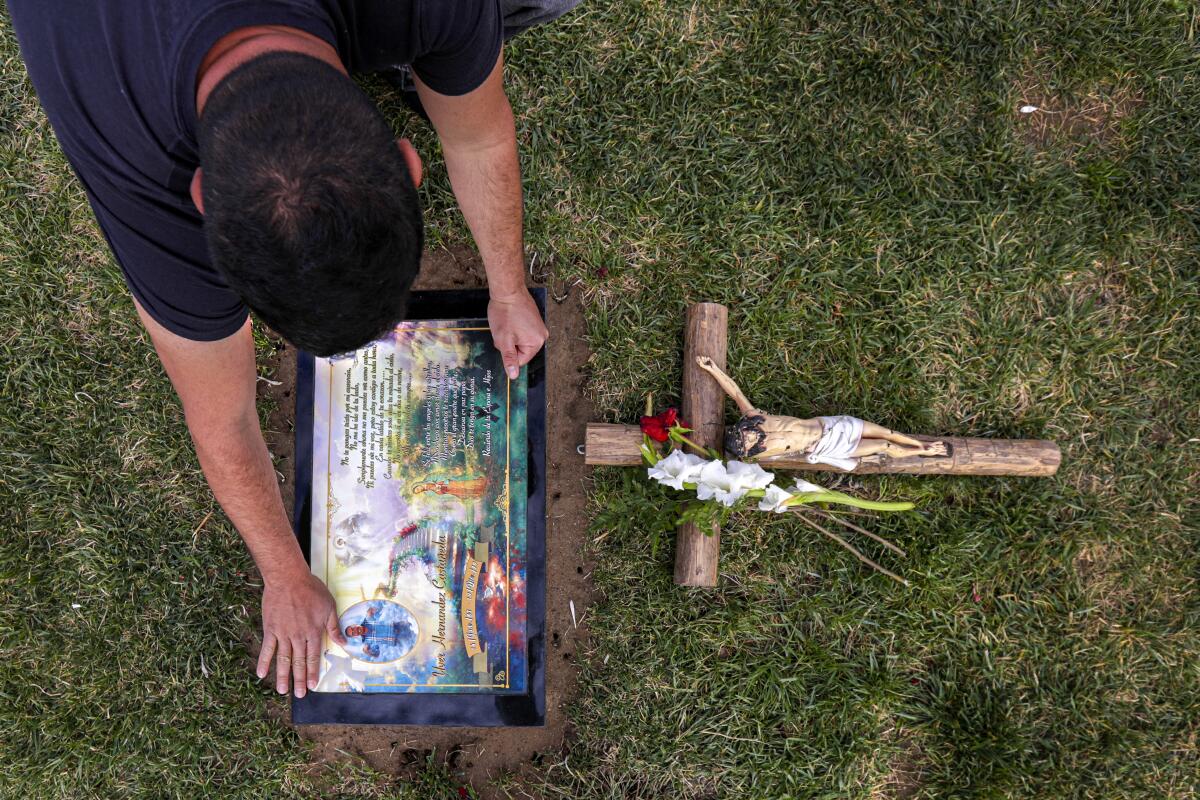 A man kneels over a gravesite