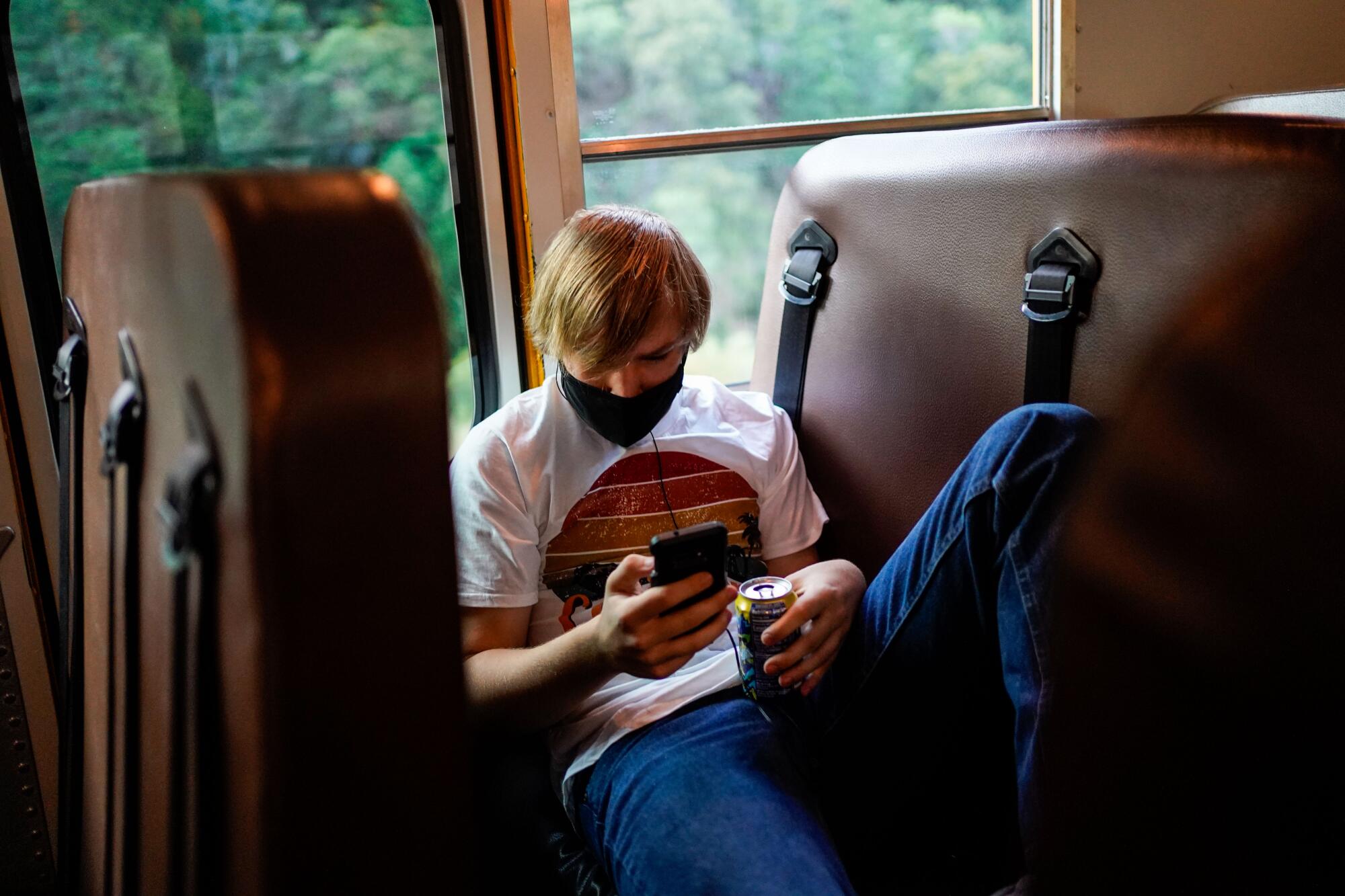 Billy Atkission, estudiante de 17 años, mira su teléfono mientras va en el autobús a la escuela.