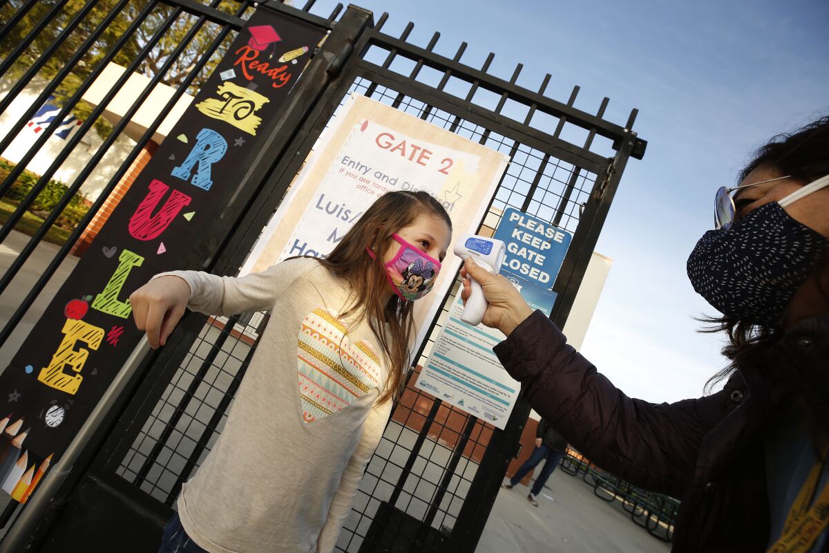 First-grader Braylen Coleman has her temperature taken by teacher's aide Firoozeh Borjian.
