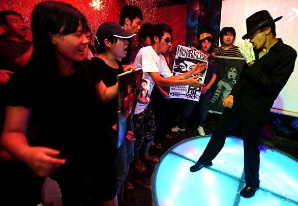 A Chinese fan of Michael Jackson imitates the pop singer as people gather to commemorate him at a bar in Beijing.
