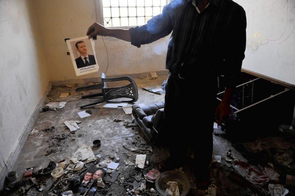 A man holds up a picture of Syrian President Bashar Assad at a former police station in Atareb after clashes between Syrian soldiers and Free Syrain Army fighters near Aleppo.
