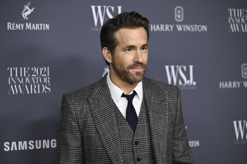A bearded man in a suit poses for cameras.