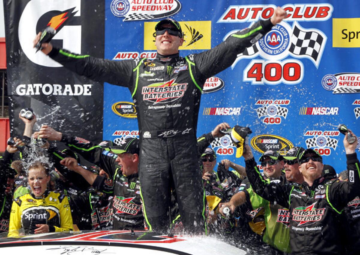 Kyle Busch, center, celebrates his victory as crew members drench his wife, Samantha, in Victory Circle on Sunday at Auto Club Speedway in Fontana.
