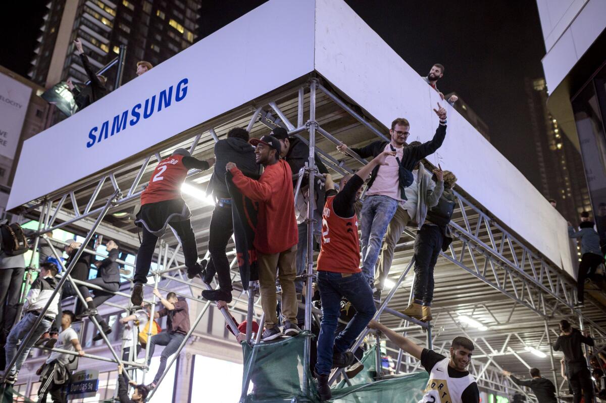 Raptors fans climb scaffolding in downtown Toronto to celebrate the team's NBA championship.