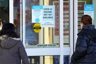 Customers wear a mask as they check out information signs that a COVID-19 vaccine is not yet available at Walgreens in Northbrook, Ill. 