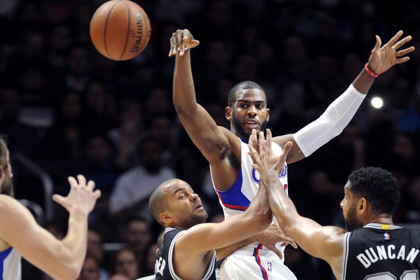 Clippers point guard Chris Paul leaps to make a pass to teammate Spencer Hawes over Spurs point guard Tony Parker and forward Tim Duncan in the first half.