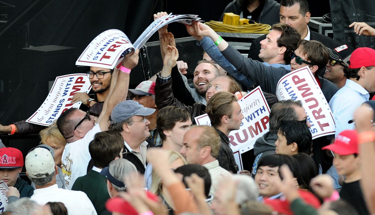 Trump supporters grab signs before a rally at the Orange County Fairgrounds in Costa Mesa.