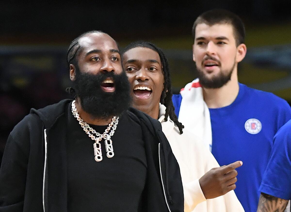 James Harden, left, is in street clothes as he stands near new teammates Terance Mann, center, and Ivica Zubac by the bench.