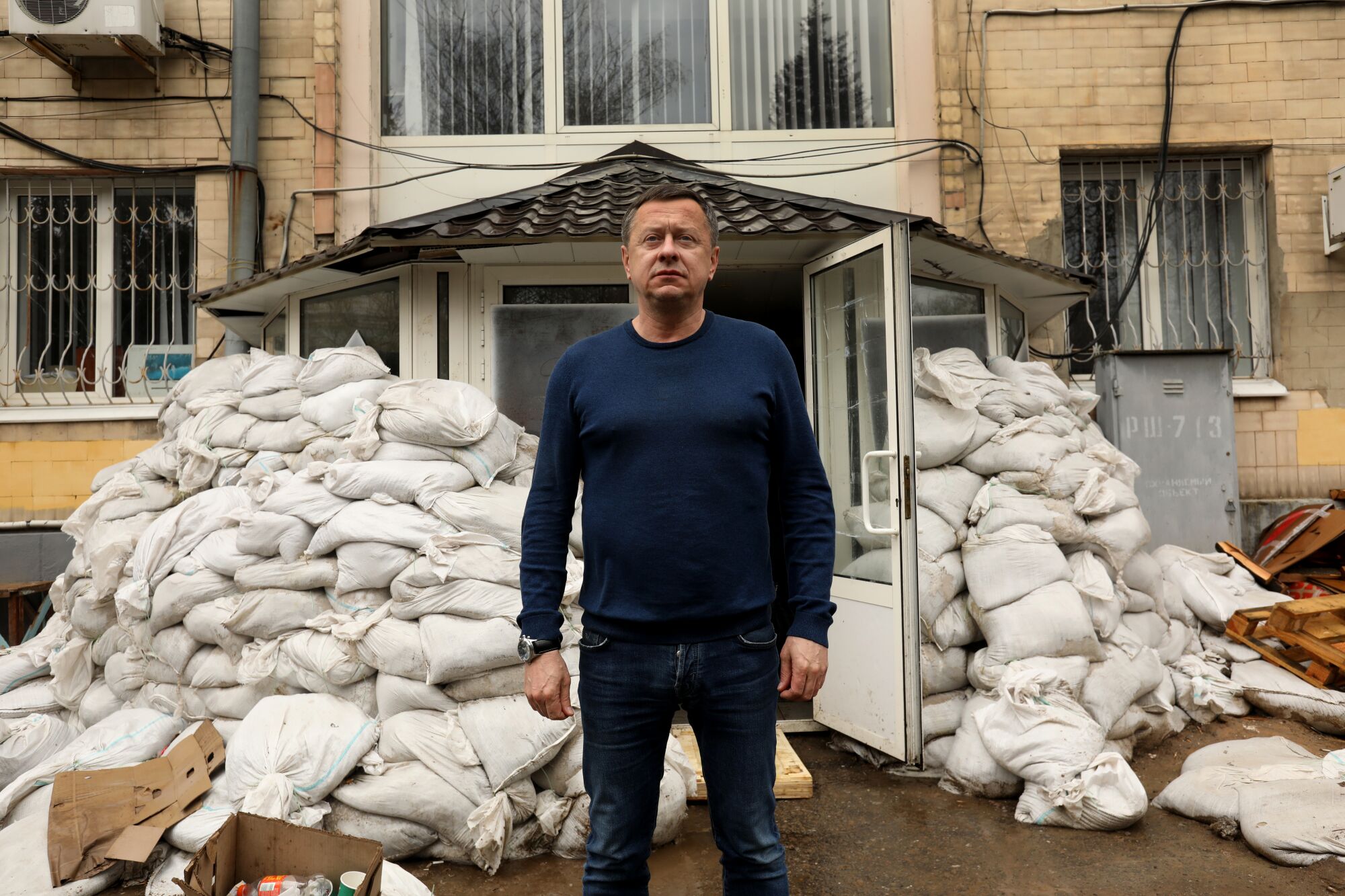 A man stands next to sandbags.