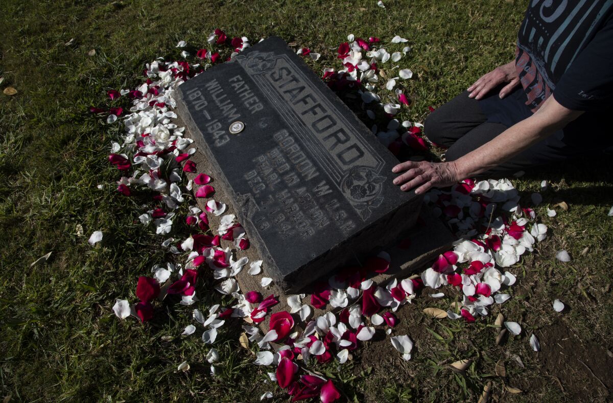 Linda Dudik rests her hand on the grave of Seaman Gordon Stafford at San Marcos Cemetery.  