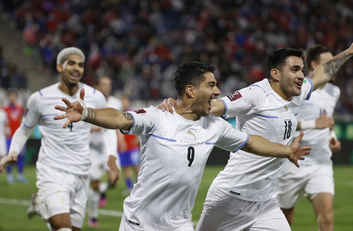 Uruguay's Luis Suarez, center, celebrates scoring his side's opening goal against Chile during a qualifying soccer match for the FIFA World Cup Qatar 2022 at San Carlos de Apoquindo stadium in Santiago, Chile, Tuesday, March 29, 2022. (Alberto Valdes/Pool Via AP)