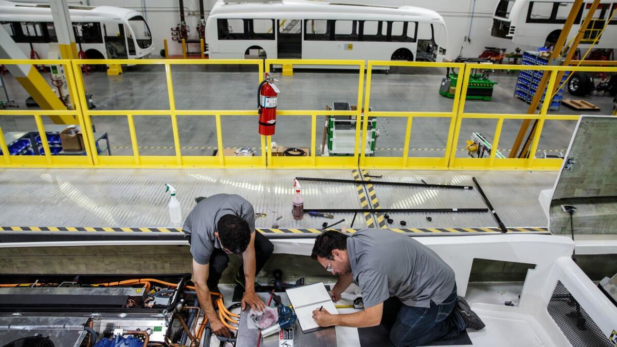 Workers assemble the air-conditioning unit for an electric bus made by Proterra at a factory in Los Angeles.