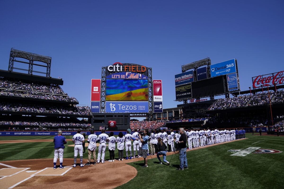 The Ukrainian flag is display in solidarity during opening ceremonies before a baseball game between the New York Mets and the Arizona Diamondbacks, Friday, April 15, 2022, in New York. (AP Photo/John Minchillo)