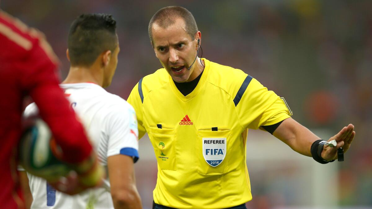 Referee Mark Geiger explains a call during a 2014 World Cup game between Chile and Spain.