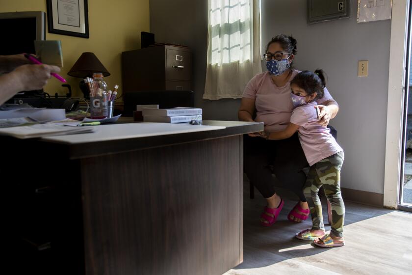 LIVINGSTON, CA - OCTOBER 15, 2020: Undocumented worker Janette Hernandez with her daughter Janely, 5, sits in Rev. Frances Le Bas's office to receive a $1,000 check to help cover expenses since the coronavirus pandemic has hit essential Latino workers very hard in the San Joaquin Valley on October 15, 2020 in Livingston, California. (Gina Ferazzi / Los Angeles Times)