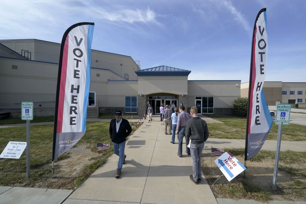 People wait to cast their ballot on the first day of early voting at an advance polling location Saturday, Oct. 17, 2020, in Overland Park, Kan. (AP Photo/Charlie Riedel)