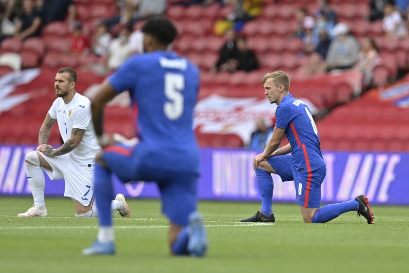 England's and Romania's players take a knee before the international friendly soccer match between England and Romania in Middlesbrough, England, Sunday, June 6, 2021. (Paul Ellis, Pool via AP)