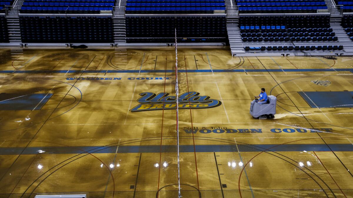 A worker tries to remove water from the Pauley Pavilion court after a water main break under Sunset Boulevard flooded part of the UCLA campus.